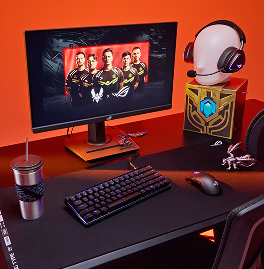 A tabletop with a full setup, glowing orange with the background lighting and a monitor inscreen of Team Vitality.