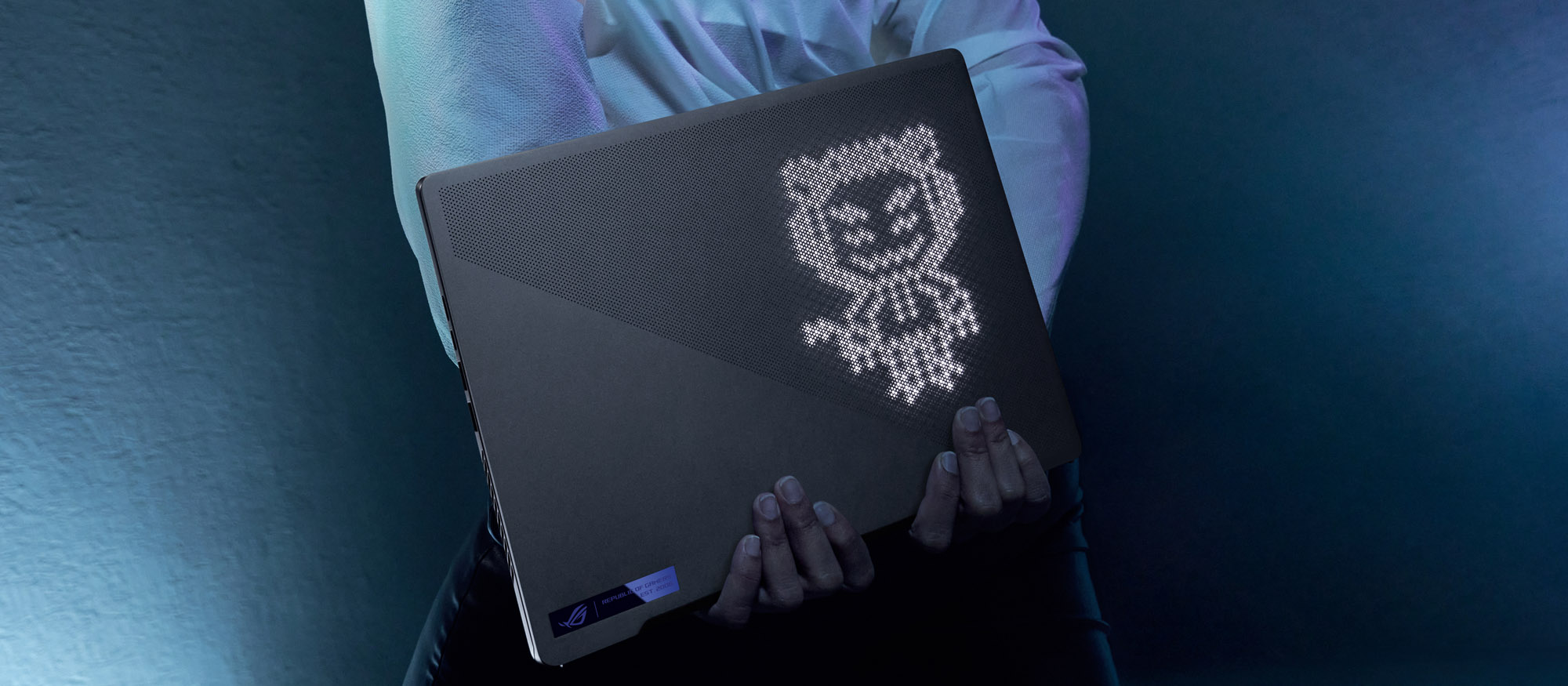 Person holding Zephyrus G14 behind their back, with OMNI visible on the AniMe Matrix screen.