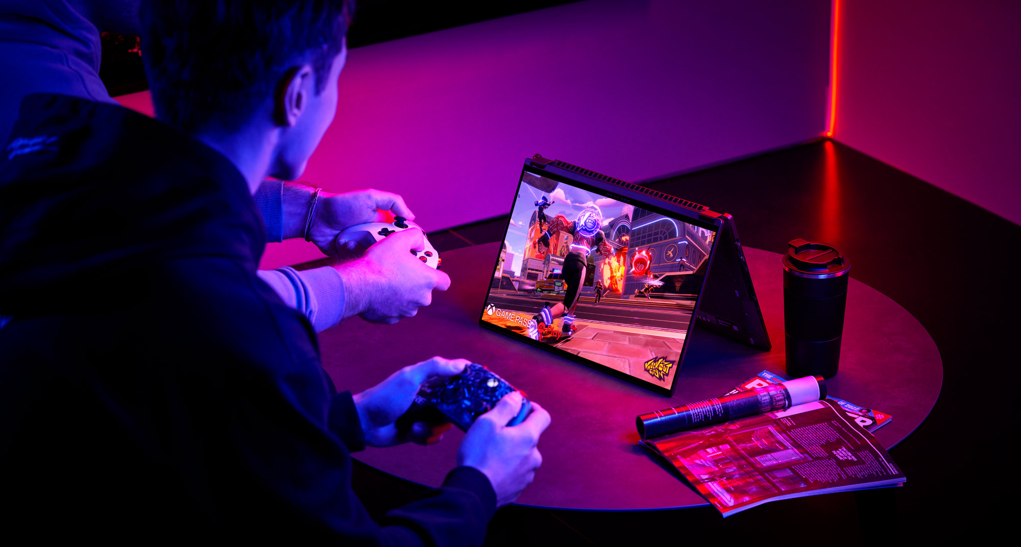 An image of two people playing video games on the ROG Flow X16 in tent mode, using game controllers.