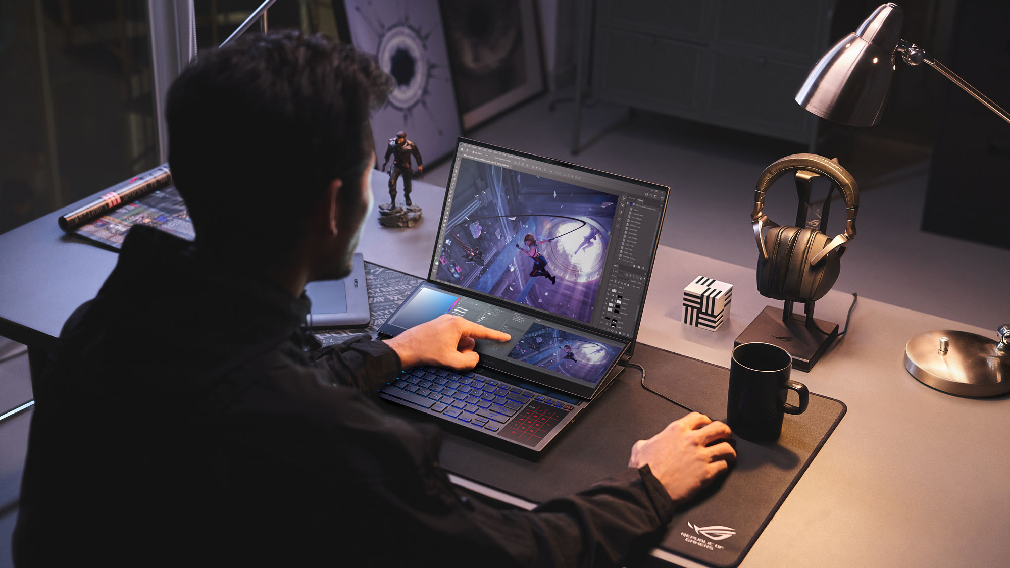 A photo of the Zephyrus Duo 16 on a table, with a user holding a mouse and touching the ScreenPad Plus secondary display.