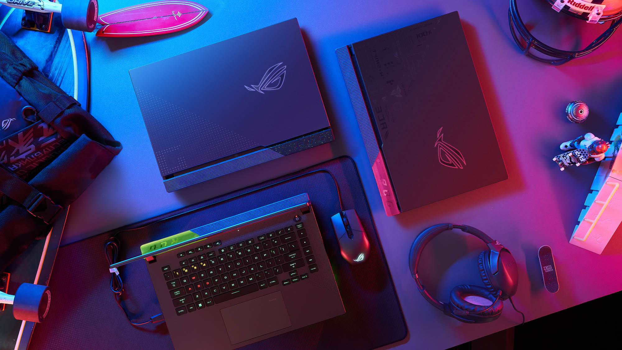 Three Strix G laptops laid out on a table, showcasing different color schemes.