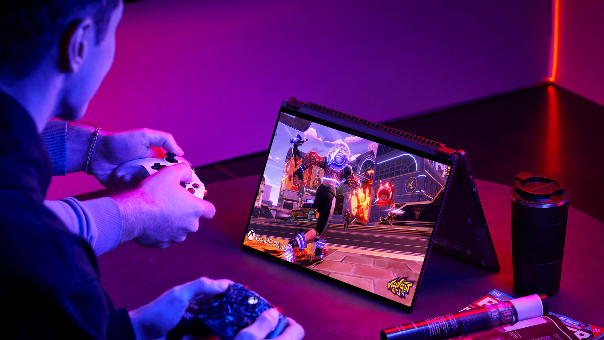 Фотография двух человек, играющих в игры на ноутбуке Flow X16 в режиме палатки с использованием игровых контроллеров.