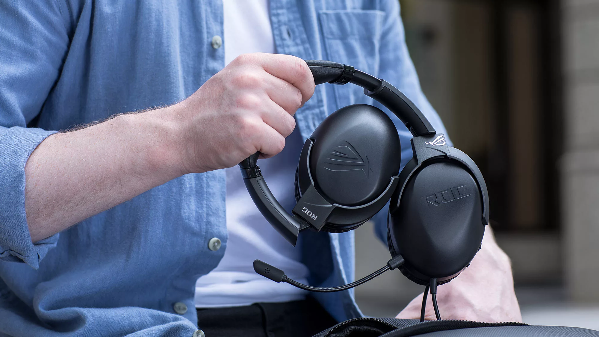 A hand placing a folded-up ROG Strix Go Core headset into a backpack.