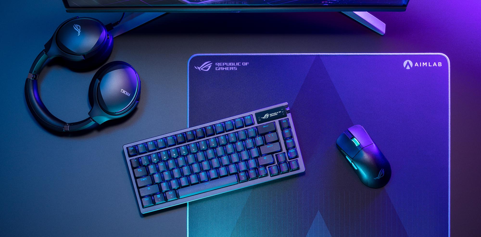 The ROG Azoth keyboard on a desk surrounded by a mouse, headset, and monitor with purple light in the background.
