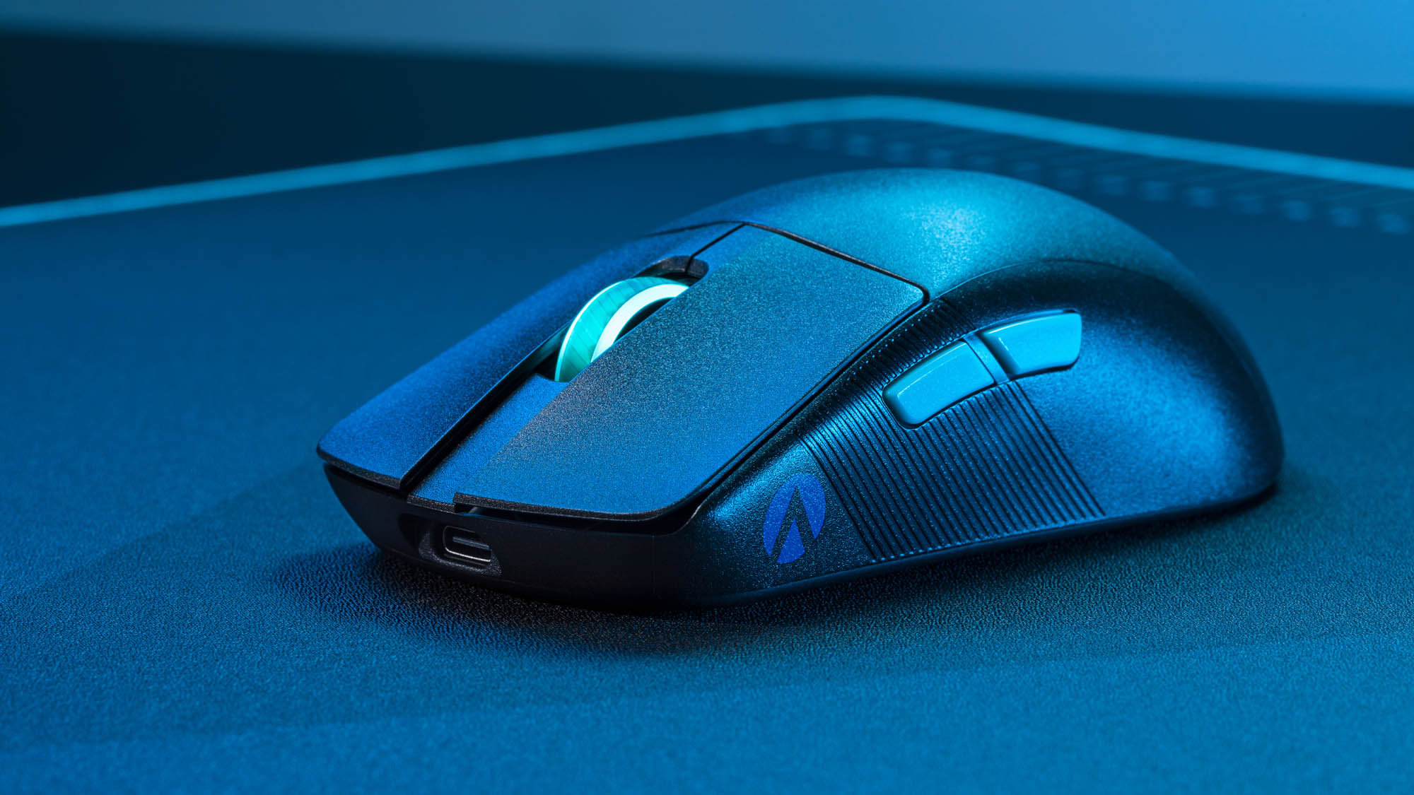 The ROG Harpe Ace mouse on a mousepad under blue lights.