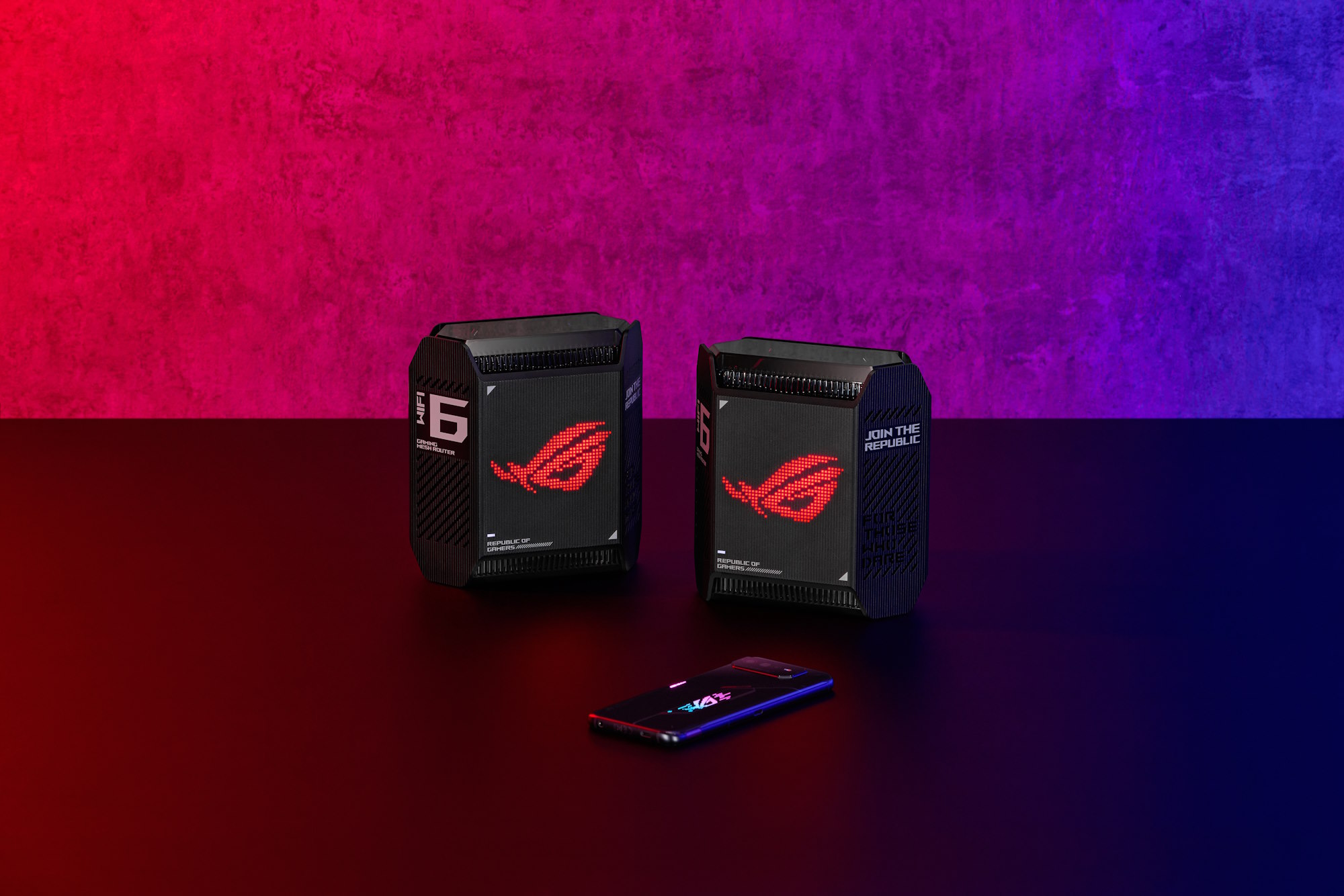 The ROG Rapture GT6 mesh WiFi system on a table with an ROG Zephyrus G14 laptop and an ROG Phone