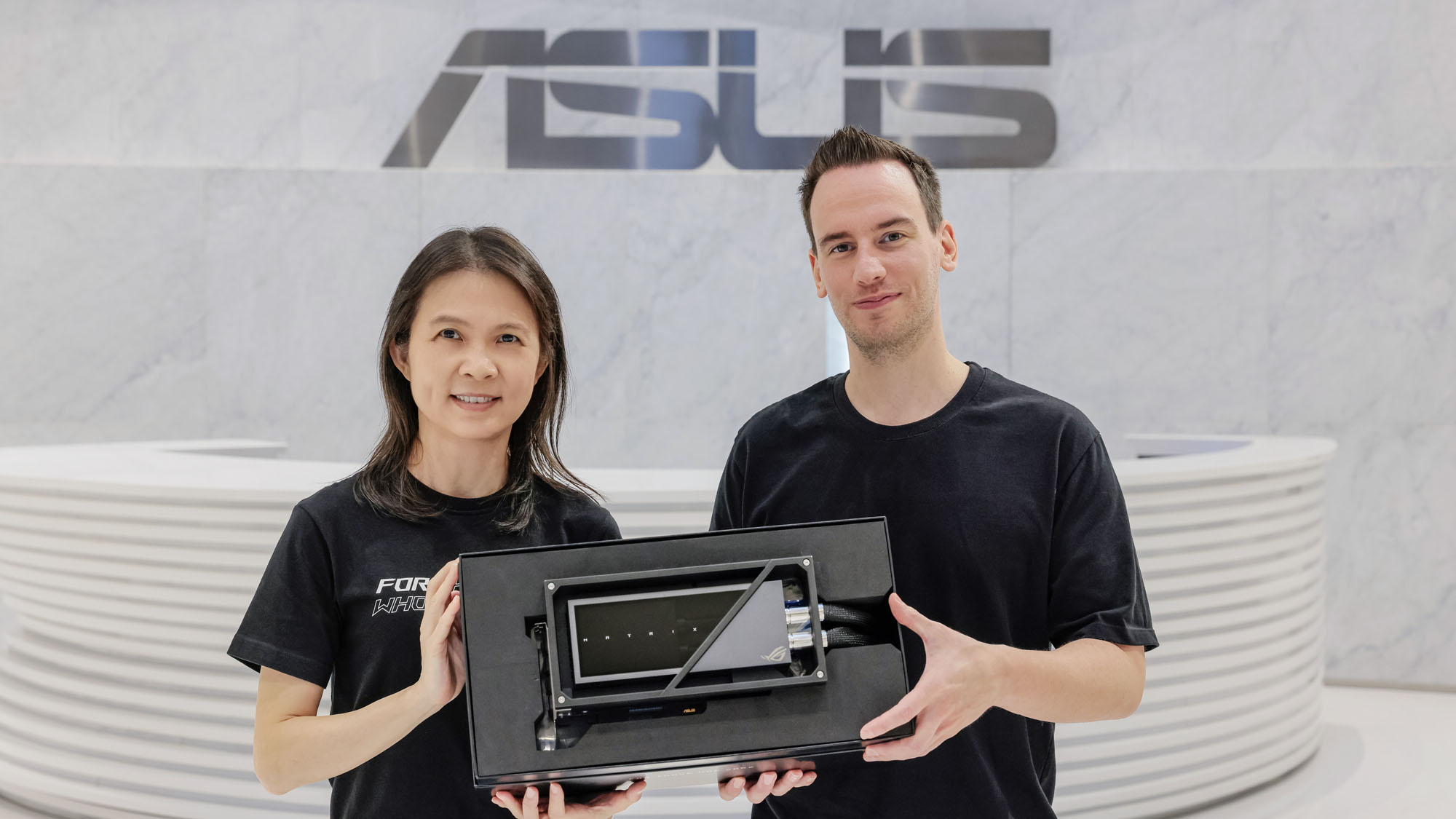 Roman Hartung and Jolene Lee holding the ROG Matrix GeForce RTX 4090 in a white marble lobby with the ASUS logo visible above them.