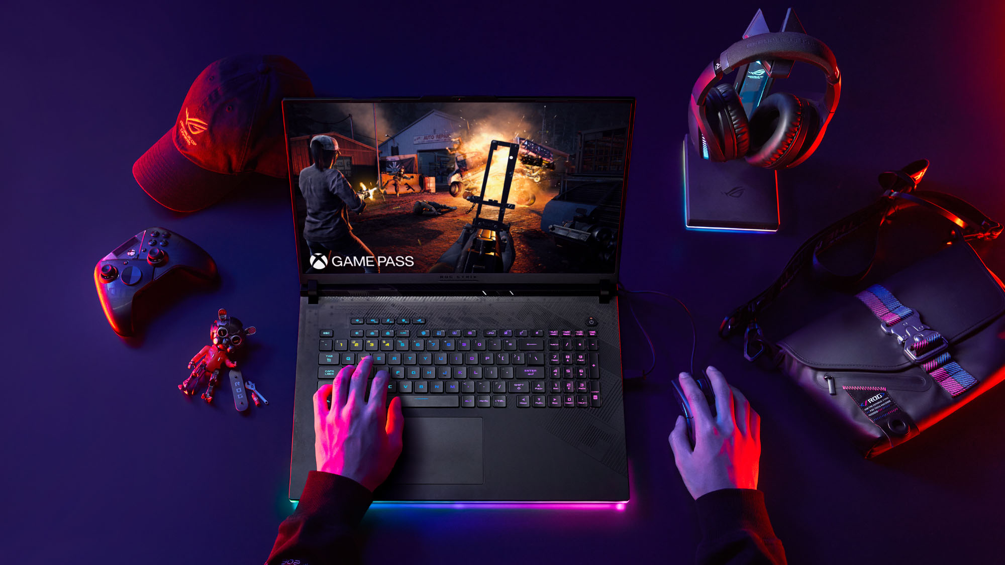 The ROG Strix SCAR 16 on a table with two hands visible playing video games.