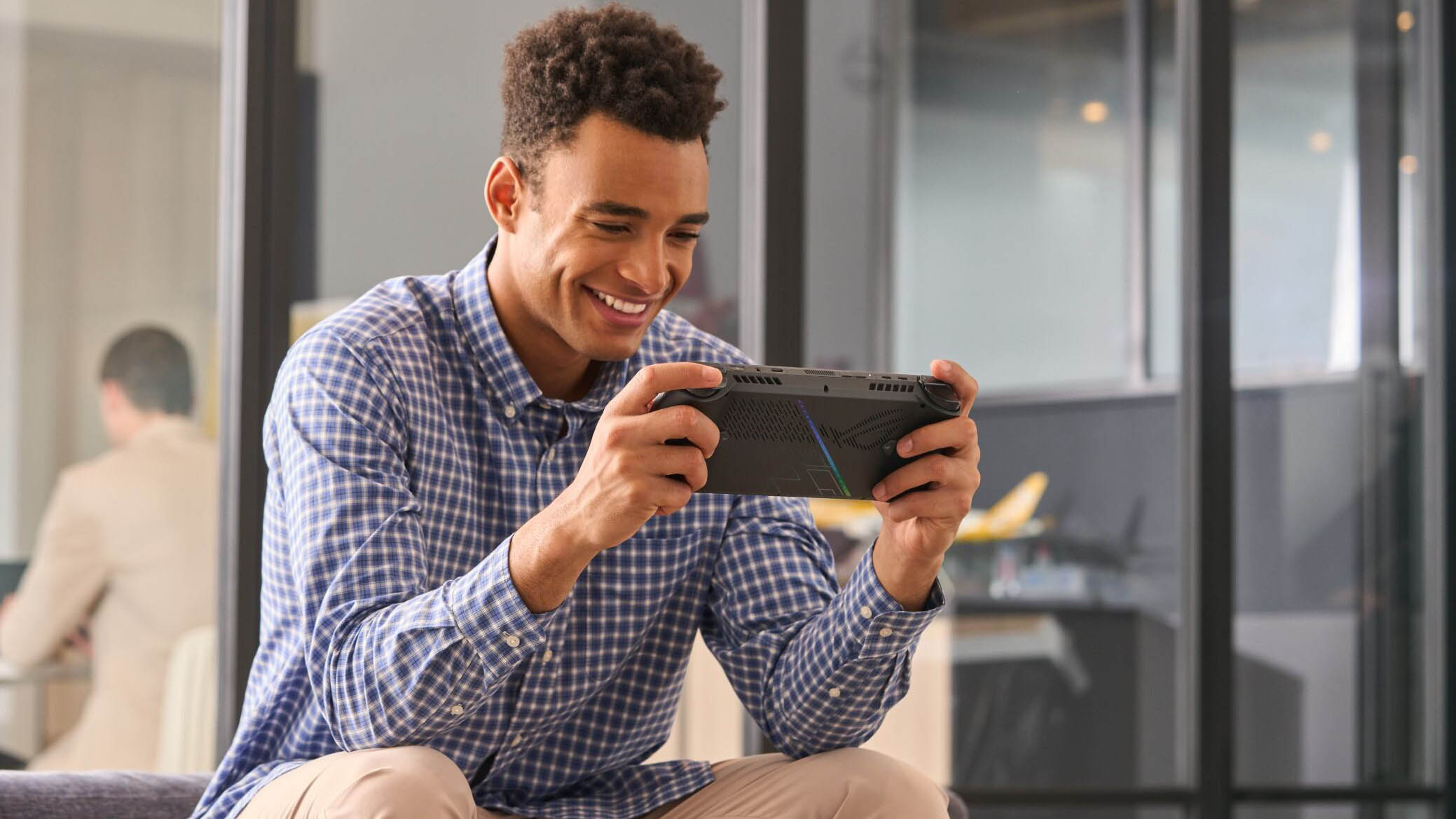 A man playing the ROG Ally on a couch.