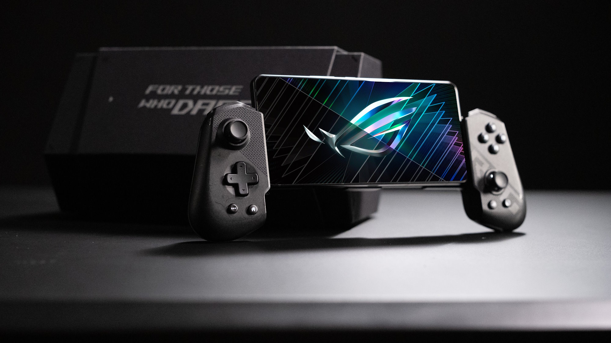 The ROG Tessen mobile controller installed on the ROG Phone 8 in front of its mounting box on a table