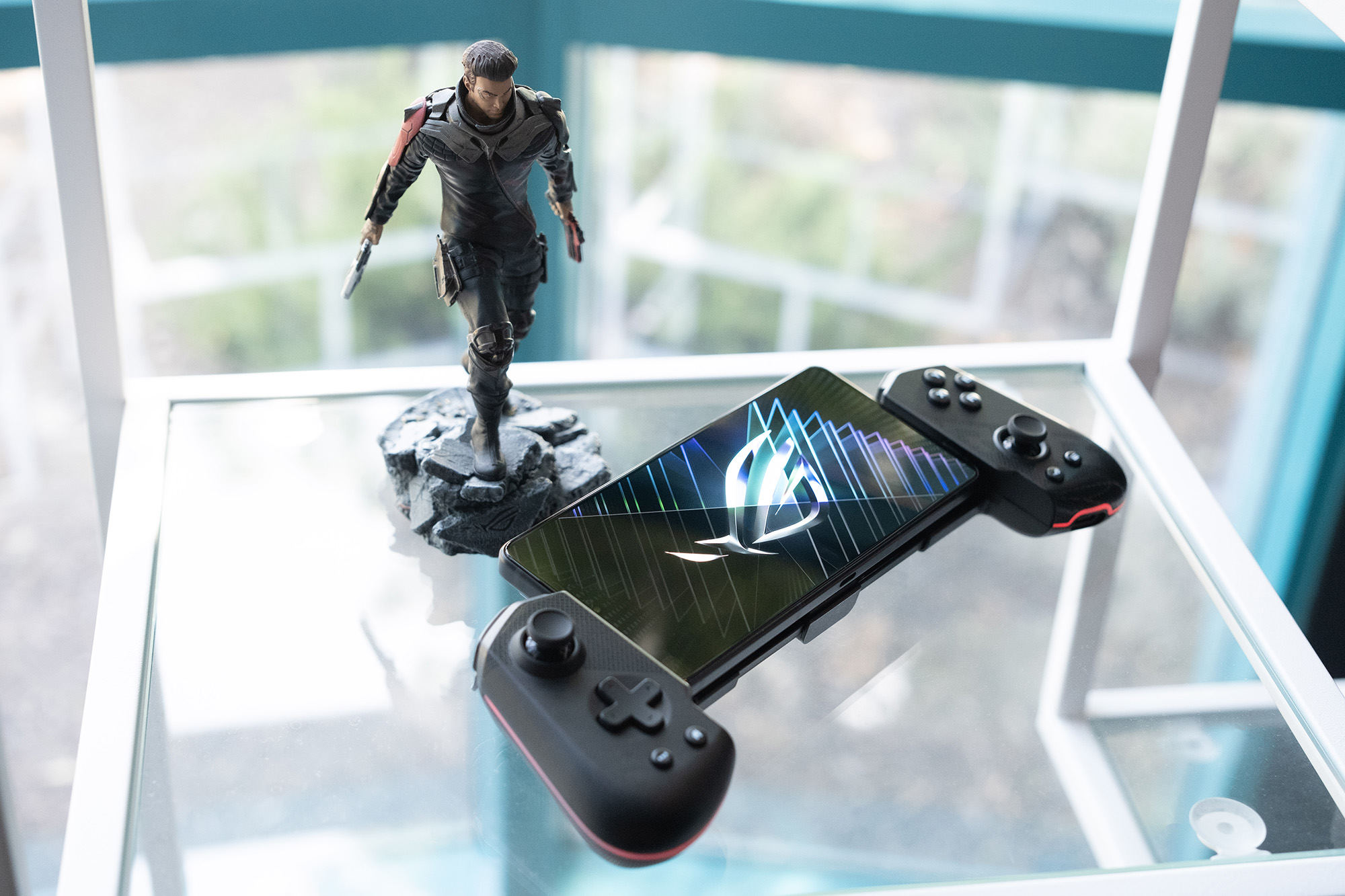 The ROG Tessen and ROG Phone 8 on a glass table with an ROG figurine nearby