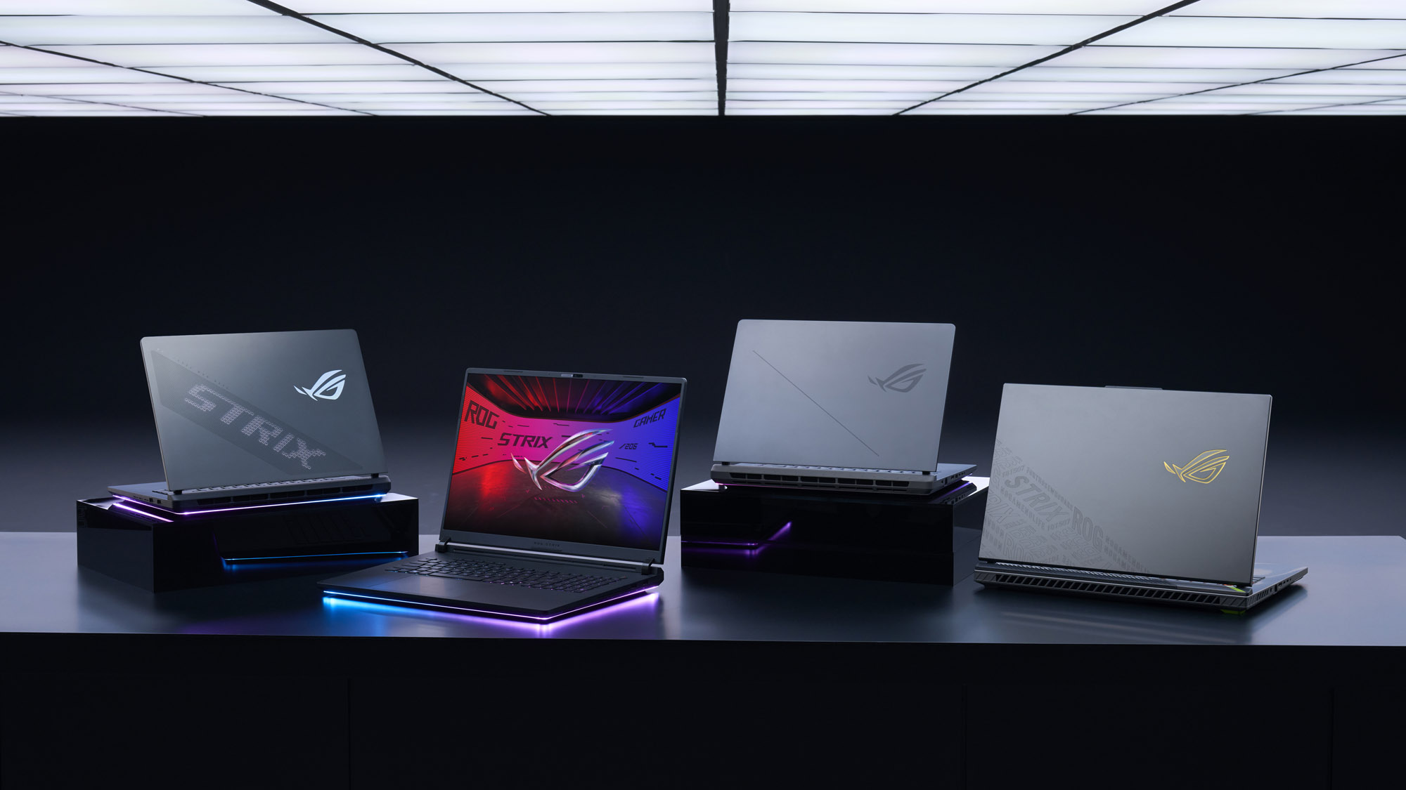 The 2025 Strix laptop range displayed on a table in a dimly lit room.