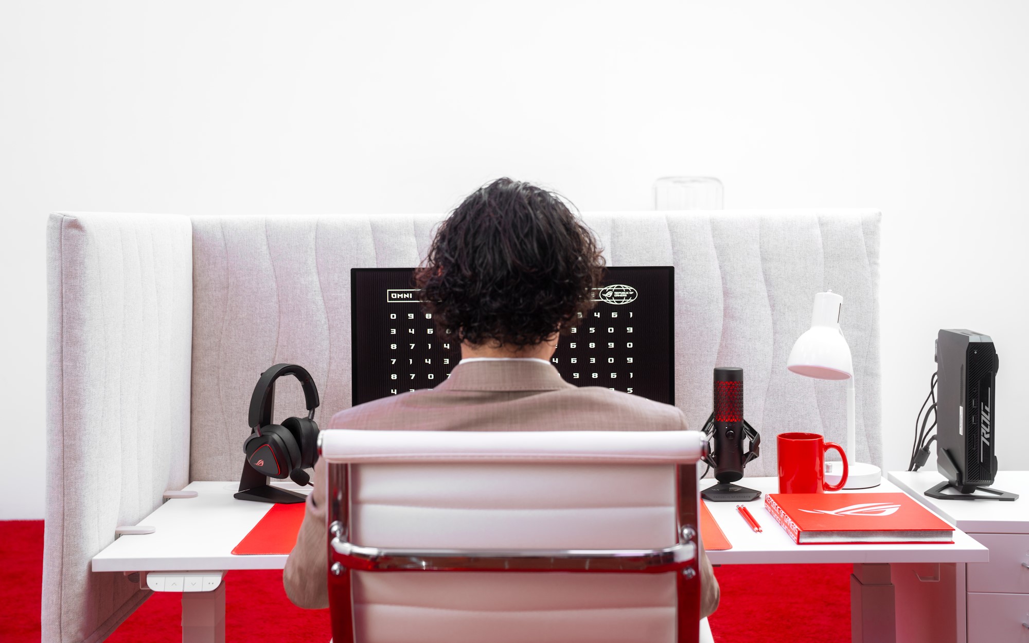 A view of the back of a young man's head as he works at an office desk