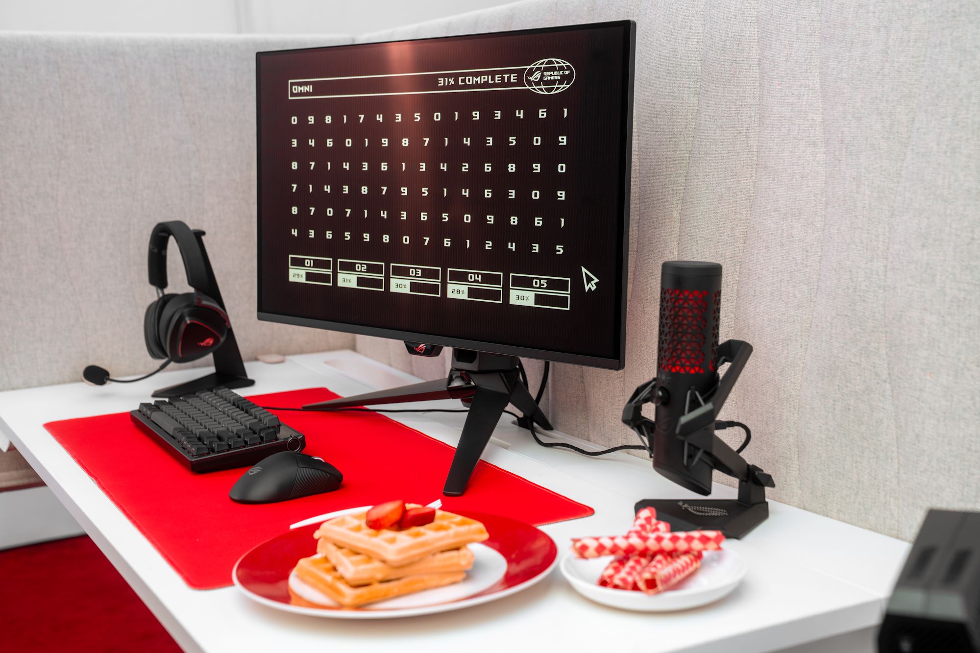 A computer station with ROG gear, with two plates in the foreground, one with waffles and one with fingertraps