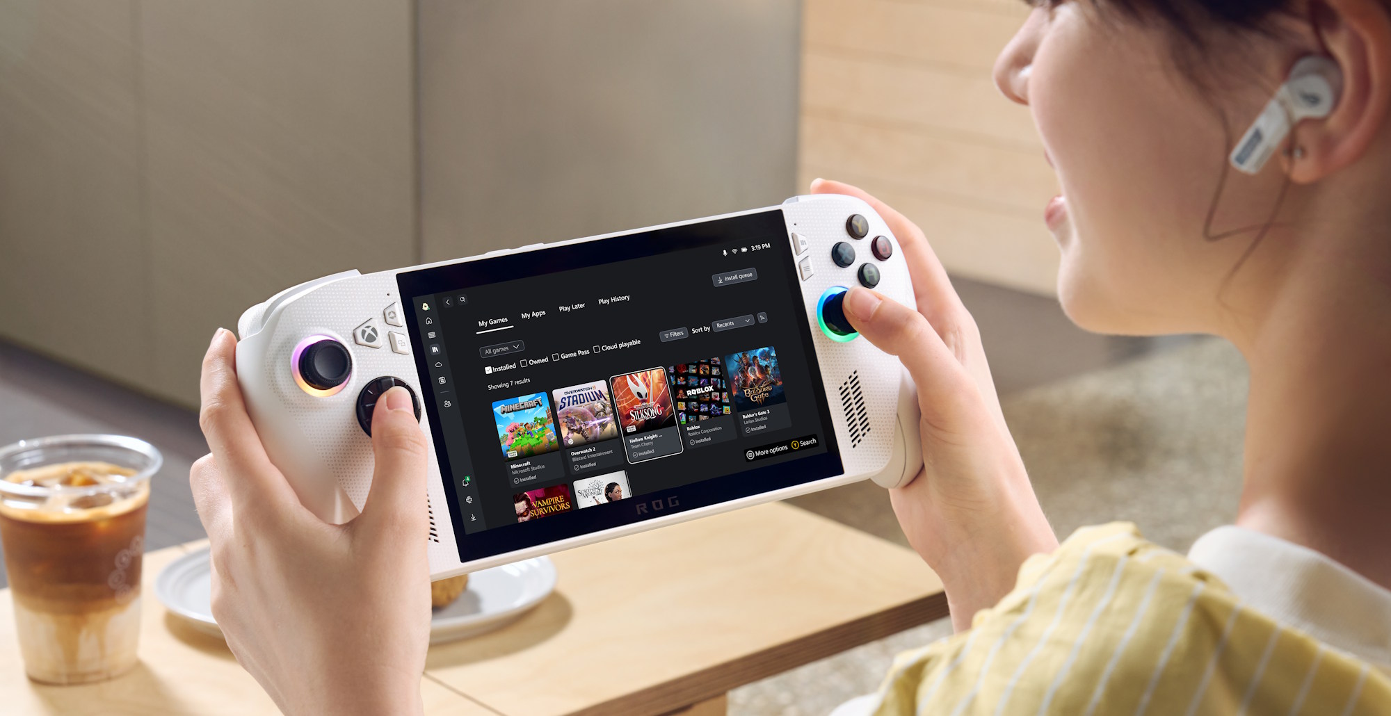 A woman holding the ROG Xbox Ally in her hands, with the Xbox app visible on screen.