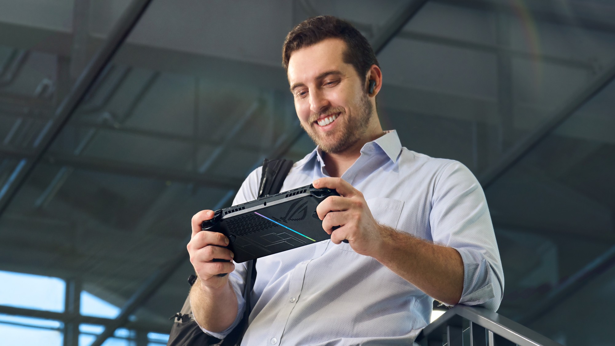 A man smiling and holding the ROG Xbox Ally X, with the rear of the device visible.