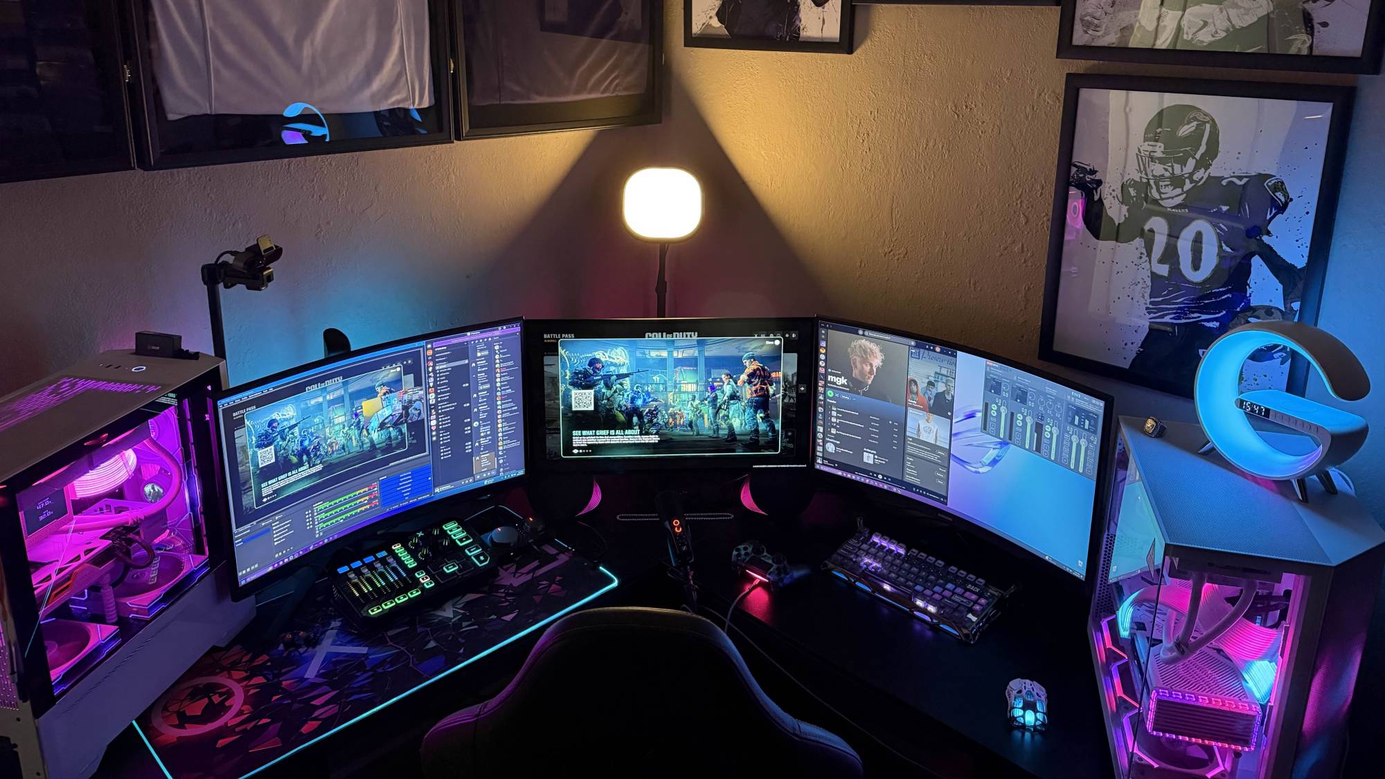 Discord user ItsYaBoyAtown's PC setup featuring two desktops, three monitors, and a lot of framed football player posters, all set against warm indoor lighting.