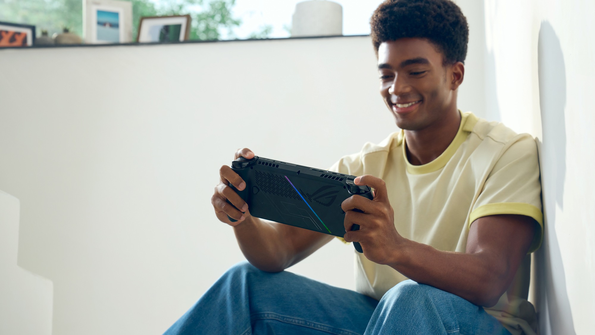A man playing the ROG Xbox Ally X, with the back of the handheld visible