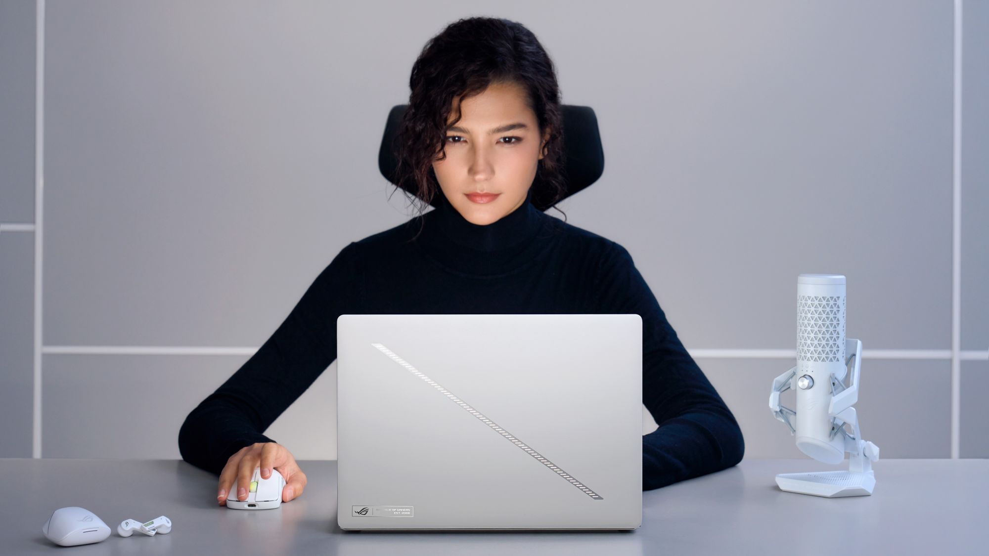 A woman uses the 2025 ROG Zephyrus G14 while seated at a gray desk