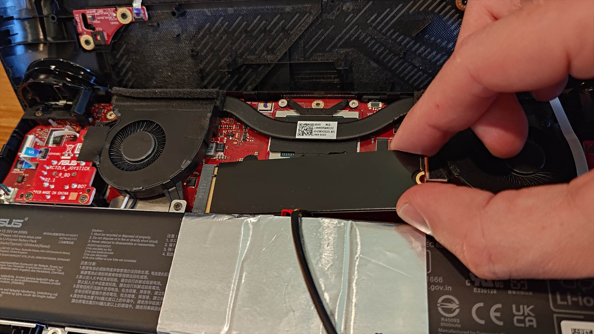 A hand removing the SSD from the ROG Ally X