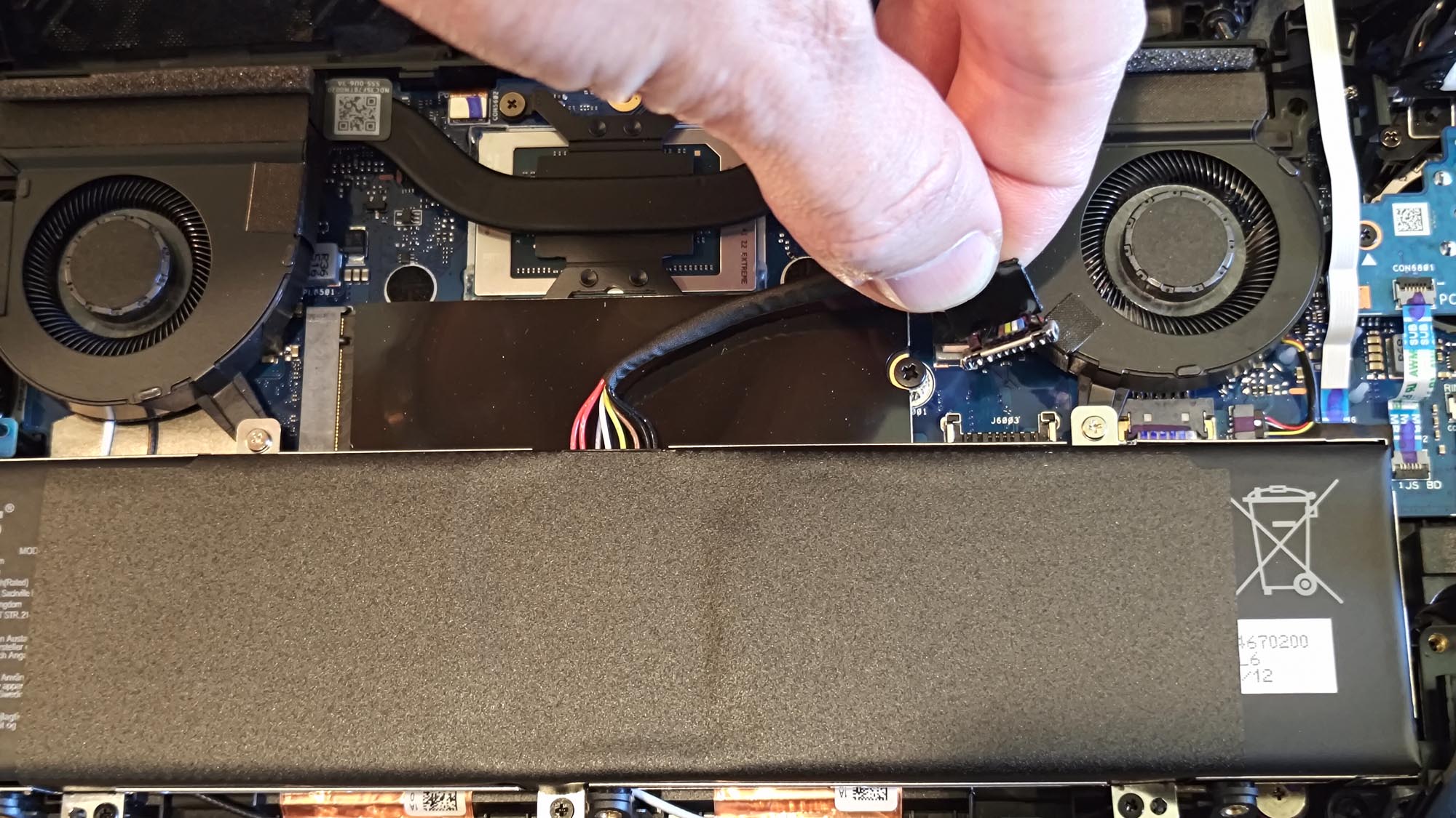 A hand disconnecting the battery cable of the ROG Xbox Ally X