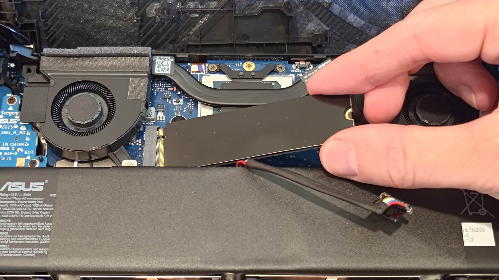 A hand removing the SSD from the ROG Xbox Ally X