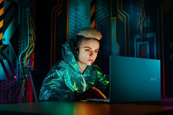 Mulher usando headset no computador, em ambiente futurista, relacionado ao metaverso.